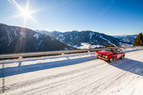 Vintage racing car driving classic rally on snow covert road