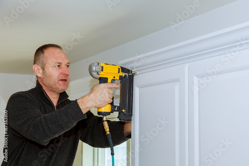 Tablou canvas Handyman working instal brad nail gun to Crown Moulding wall cabinets framing tr
