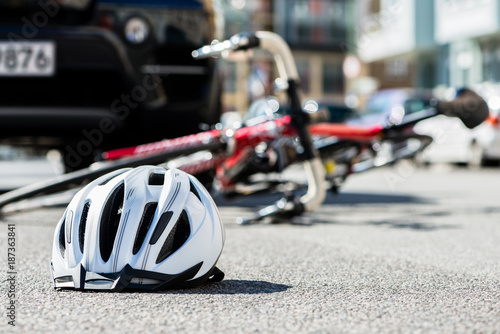 Close-up of a bicycling helmet fallen on the asphalt  next to a bicycle after car accident on the street in the city photo