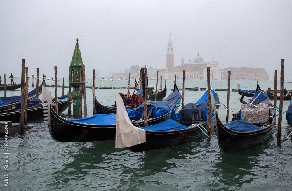 VENICE (VENEZIA) ITALY, OCTOBER 18, 2017 - View of traditional Gondolas on Canal Grande in Venice in a foggy day with San Giorgio Island on the background, Italy