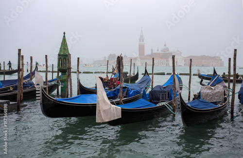 VENICE (VENEZIA) ITALY, OCTOBER 18, 2017 - View of traditional Gondolas on Canal Grande in Venice in a foggy day with San Giorgio Island on the background, Italy © faber121