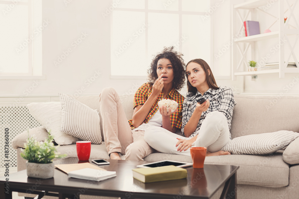 Frightened young women watching TV at home Frightened young women watching TV at home