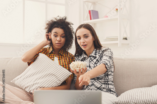 Smiling young women watching movie at home