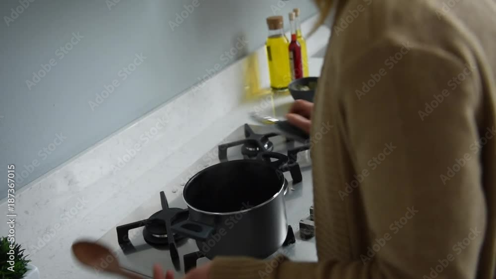housewife is cooking in the white modern kitchen housewife is cooking in the white modern kitchen