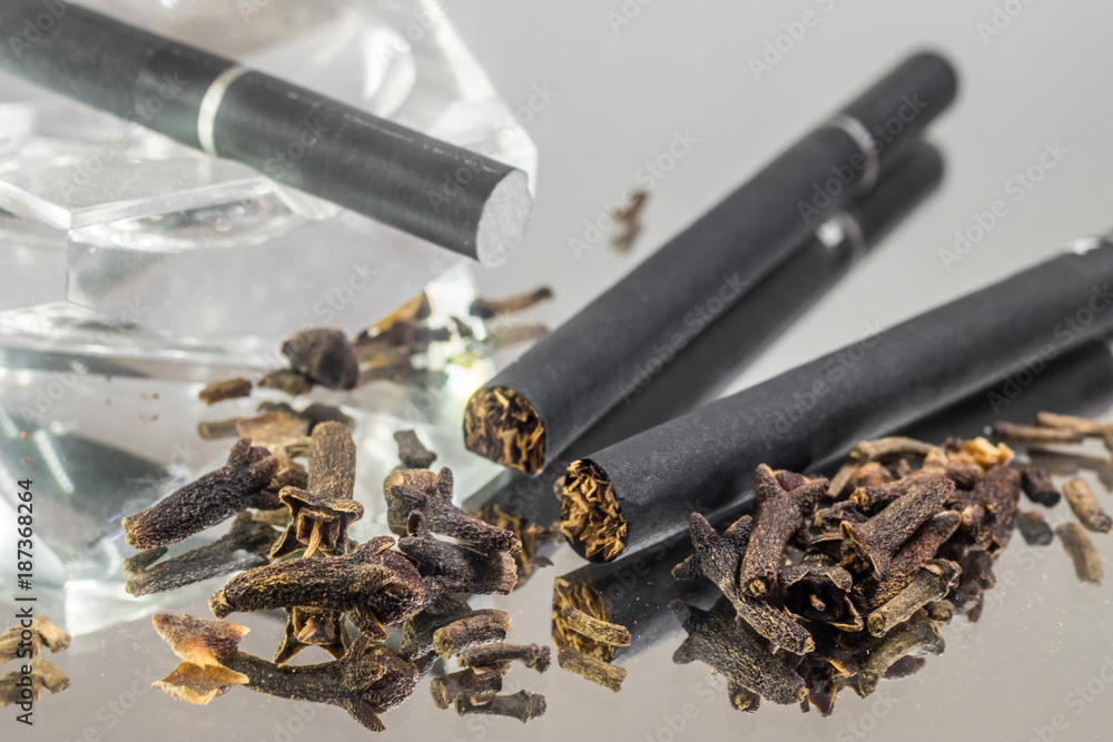 custom made wallpaper toronto digitalKretek black clove cigarretes and cloves, with a transparent glass ashtray, on top of a mirror glass reflective surface