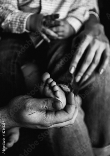 stylish black and white photo with the hands of parents and feet and the hands of their child