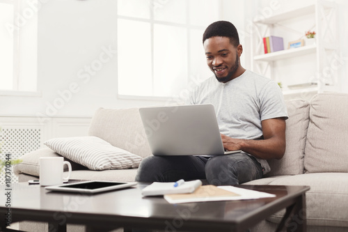 Young man at home messaging online on laptop