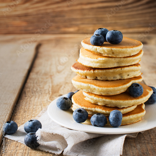 Pancakes day background, stack of homemade pancakes with blueberries over wooden table
