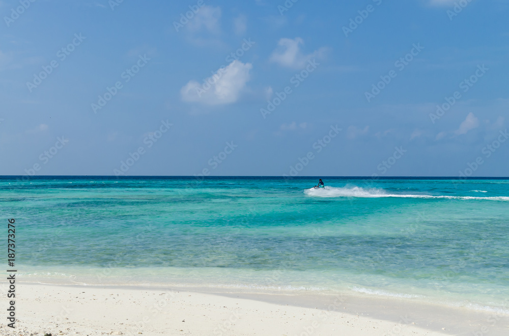 Local man riding on a jet ski in the Indian ocean at Maafushi beach. Maldives, Indian Ocean. Holidays destination