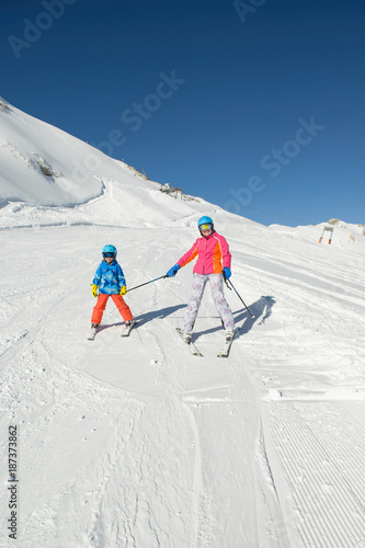 Smiling little boy with family learnt skiing during winter vacations in the mountains