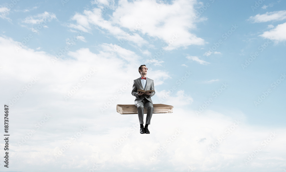 Young businessman or student floating in blue sky and studying the science