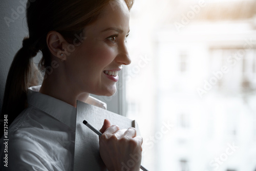 Side view pensive businesswoman keeping day planner in hand. Copy space. Dreaminess and labor concept