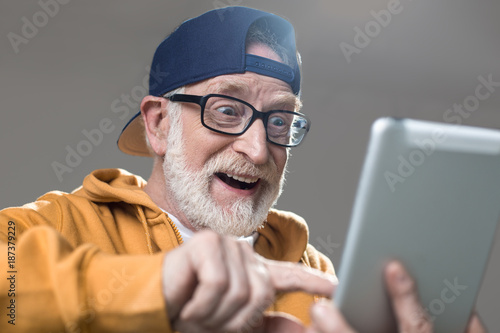 Fotótapéta Amused old man in sportswear surfing the internet on tablet