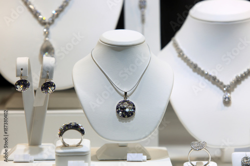 Srebrny naszyjnik, kolczyki i pierścień z diamentami na białych popiersiach w sklepie jubilerskim.