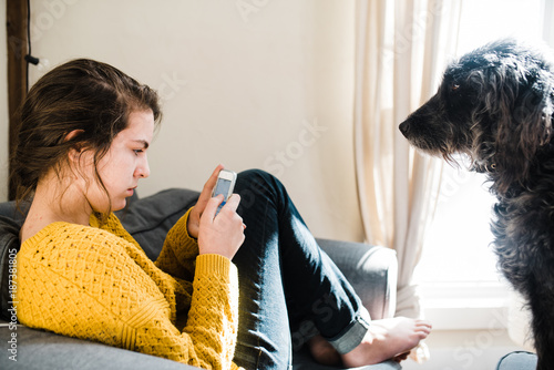 Teen on phone with dog who wants attention photo