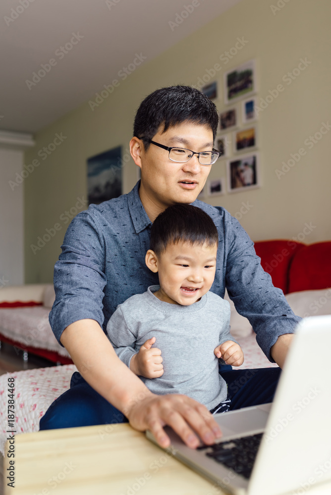 Adorable boy and his father using laptop at home Adorable boy and his father using laptop at home