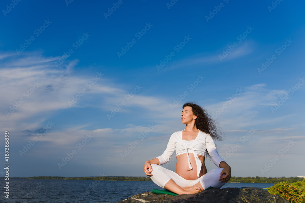 Meditating pregnant woman outdoors.