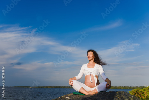 Meditating pregnant woman outdoors.