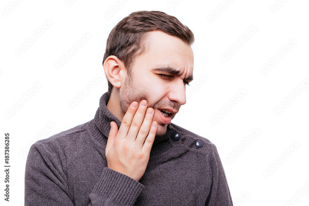 Handsome young man suffering from toothache, closeup, touching his cheek to stop pain against white background. Strong toothache Handsome young man suffering from toothache, closeup, touching his cheek to stop pain against white background. Strong toothache