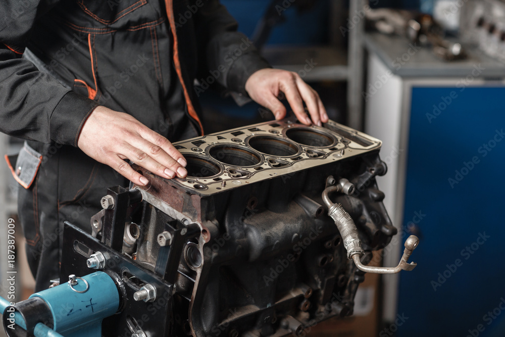 The mechanic disassemble block engine vehicle. Engine on a repair stand