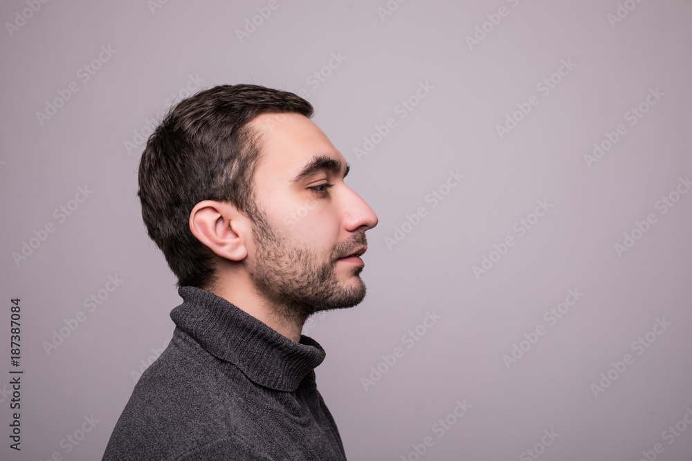 Side view portrait of thinking stylish young man looking away on gray background Side view portrait of thinking stylish young man looking away on gray background
