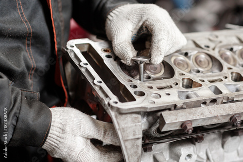 the mechanic installs a new valve. Disassemble engine block vehicle. Motor capital repair. Sixteen valves and four cylinder. Car service concept.