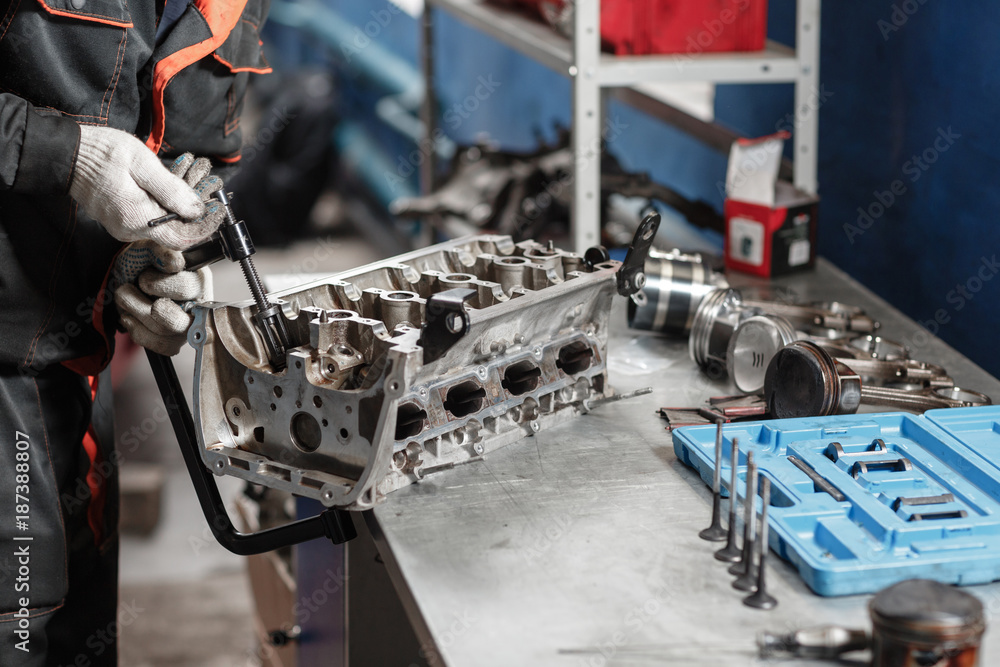 Naklejka premium the mechanic opened the locking valve mechanism. Disassemble engine block vehicle. Motor capital repair. Sixteen valves and four cylinder. Car service concept.