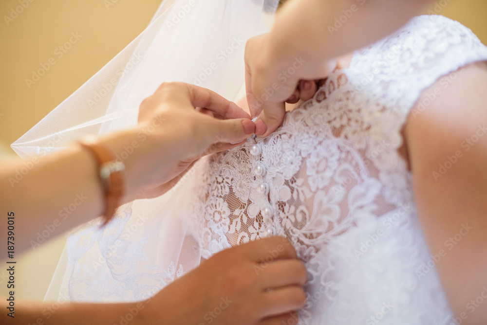 Mom helps the bride dress up a white and beautiful wedding dress