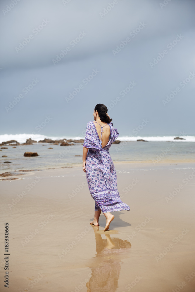 A beautiful woman walking along the beach on a dark day A beautiful woman walking along the beach on a dark day