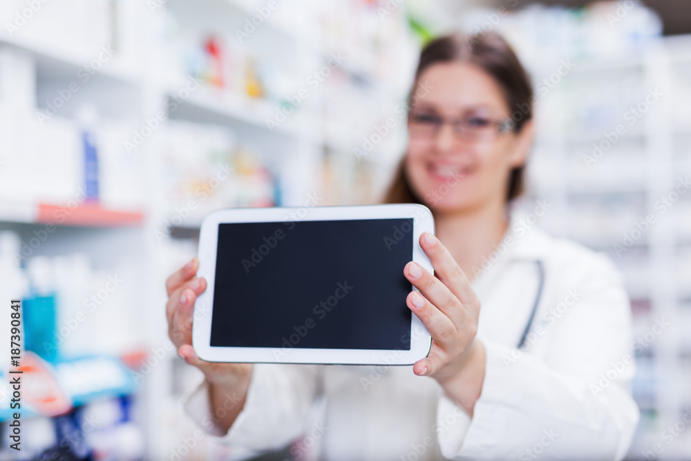 Female pharmacist holding a digital tablet smiling focus on hands and tablet screen