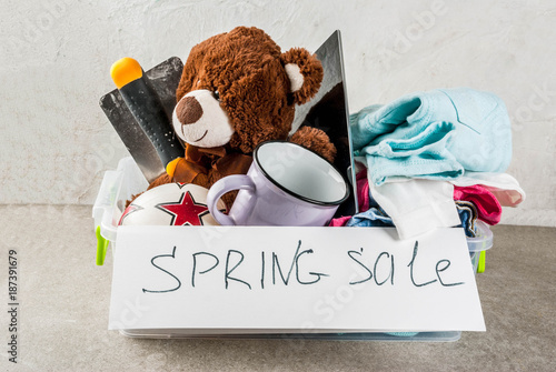 Fotografi Plastic spring sale box with toys, clothes gadgets and tools, white grey backgro