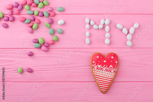 Heart shaped cookie and message. Colorful candies on pink background. Cookie made for Valentines Day. Be my Valentine.