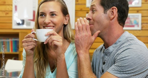 Man whispering in woman ear while coffee 