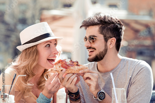 Cheerful young couple sitting in a restaurant and eating pizza.