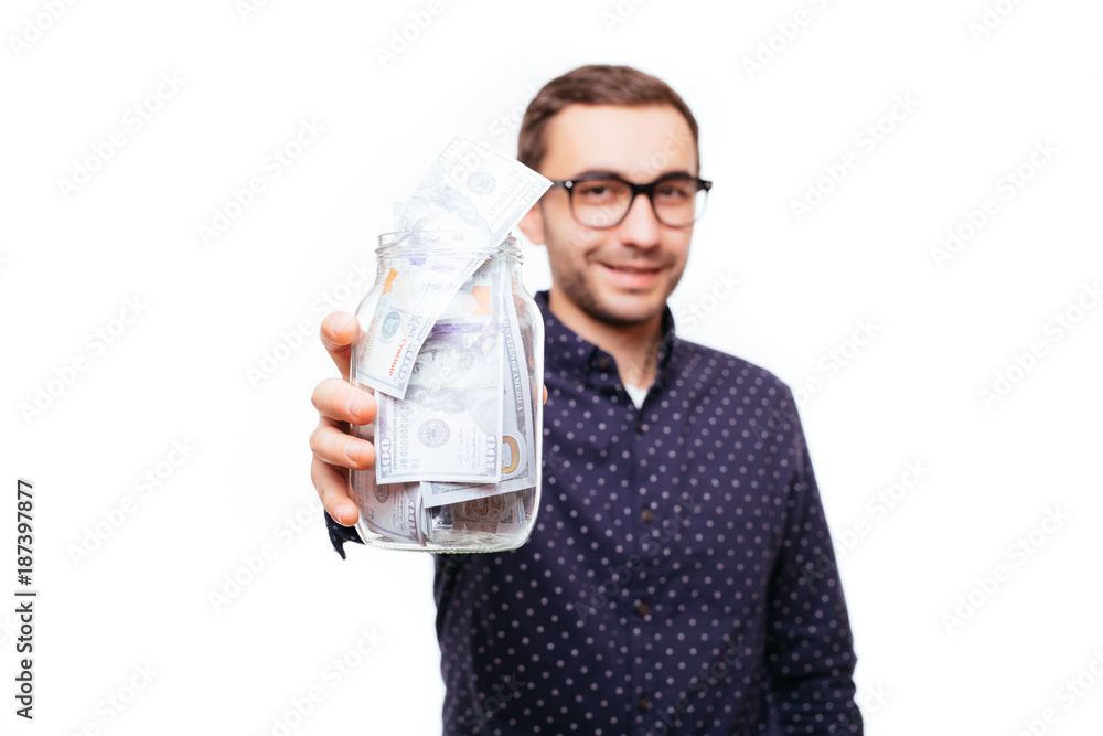 Portrait of a satisfied confident man in glasses holding jar of money banknotes isolated over white Portrait of a satisfied confident man in glasses holding jar of money banknotes isolated over white
