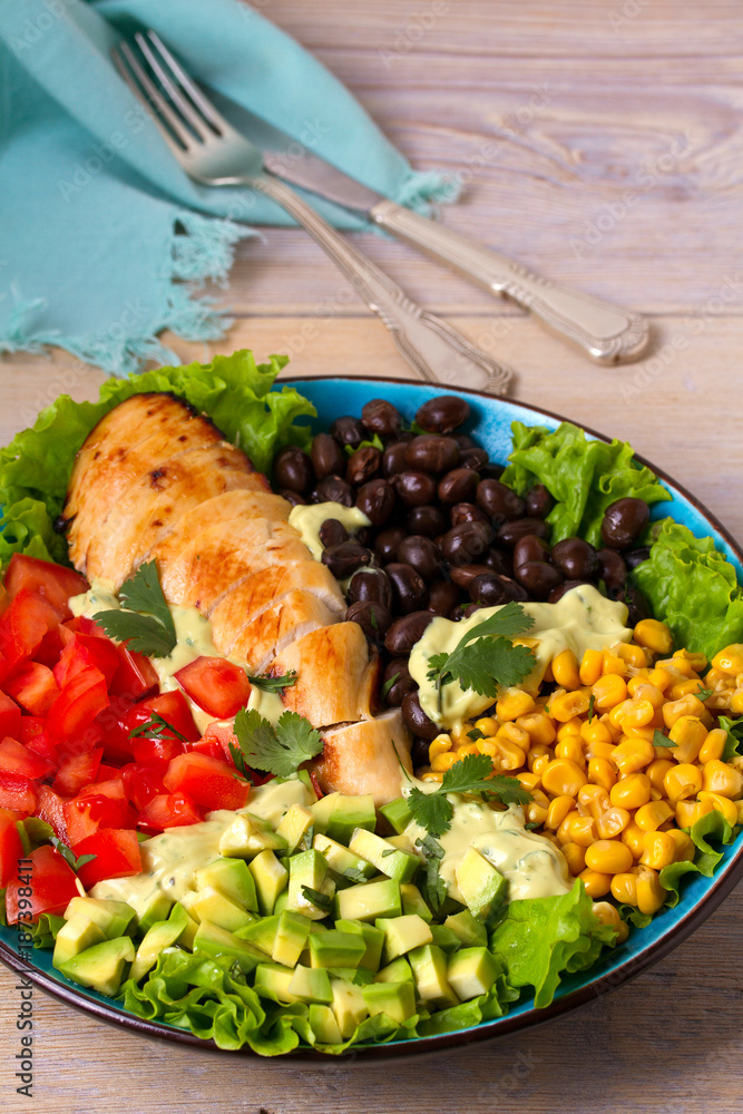 Chicken dish with nutritious selection of vegetables: avocado, beans, tomatoes and sweet corn. Chicken breast salad