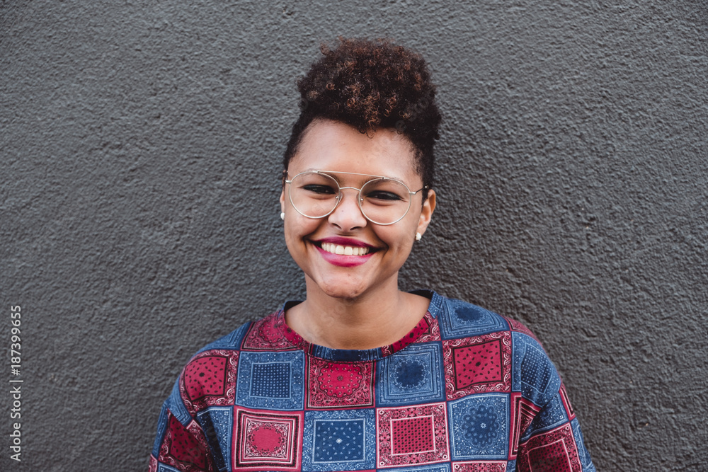 © Vera Lair/Stocksy - Woman smiling in front of a grey wall © Vera Lair/Stocksy - Woman smiling in front of a grey wall