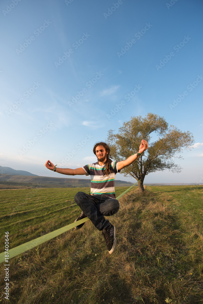 Young man sitting on slackline in lotus position Young man sitting on slackline in lotus position