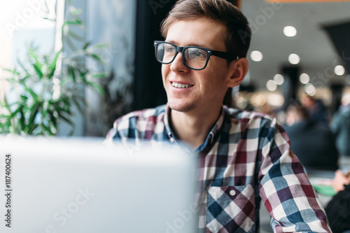 Portrait of a young man in glasses and a shirt with a positive mood and a wide smile photo