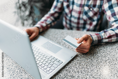 Hands close-up, male make purchases via the Internet on a laptop, credit card