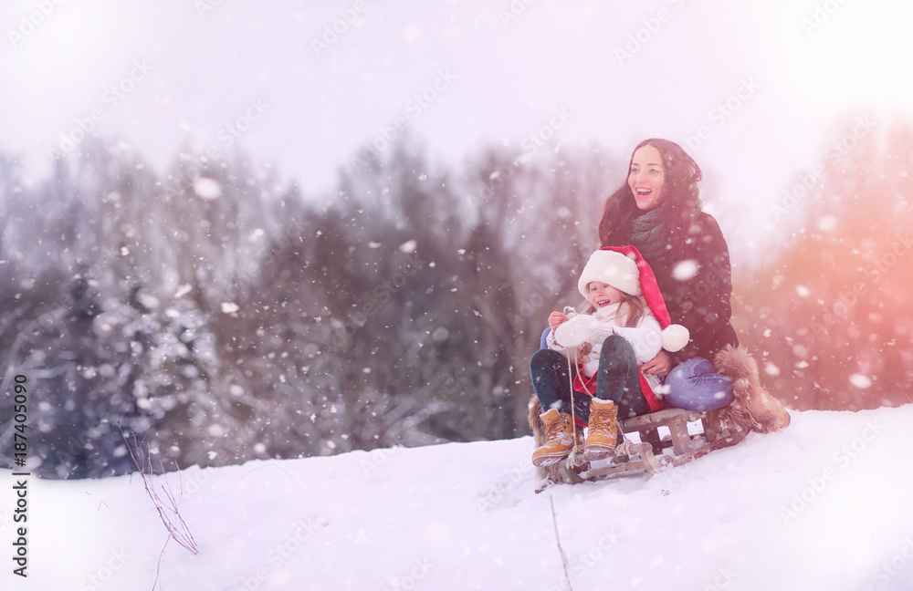 A winter fairy tale, a young mother and her daughter ride a sled A winter fairy tale, a young mother and her daughter ride a sled