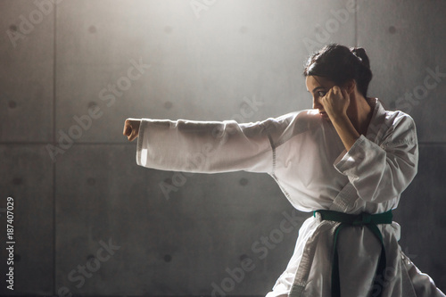 Fototapeta Koncepcja sztuk walki. Młoda kobieta w kimono ćwiczyć karate