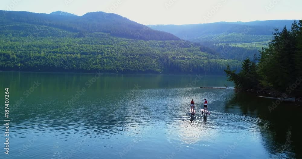 Couple rowing a stand up paddle board in the river Couple rowing a stand up paddle board in the river