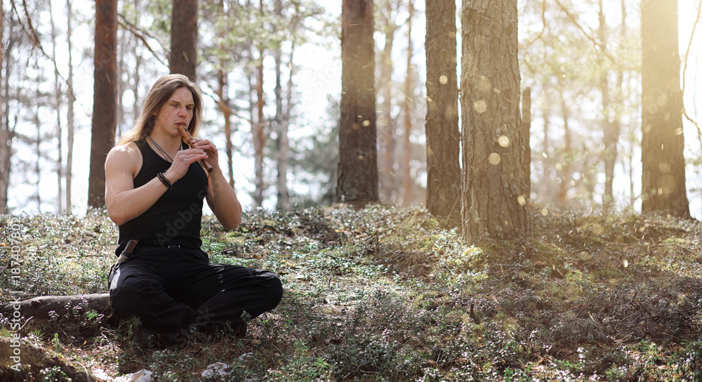 A musician with a tool in nature. A man is playing a flute in a A musician with a tool in nature. A man is playing a flute in a