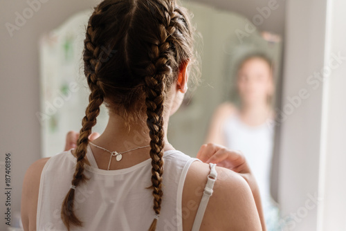 rear view of a teen girl looking at herself in the mirror