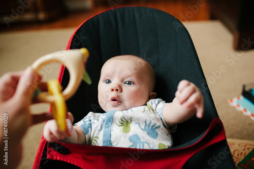 infant focusing on a rattle held in front of him by his mother