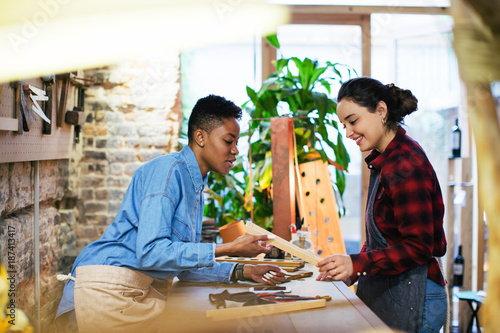 Tablou pe pânză Portrait of two smiling female carpenter in her workshop.