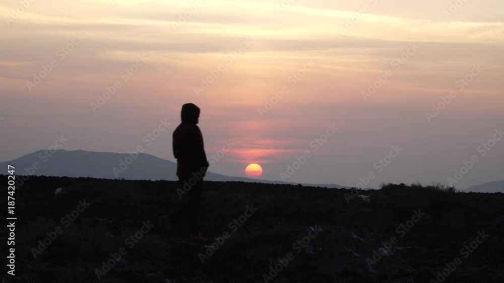 silhouette of a man walking on a hill in the background of a sunset silhouette of a man walking on a hill in the background of a sunset