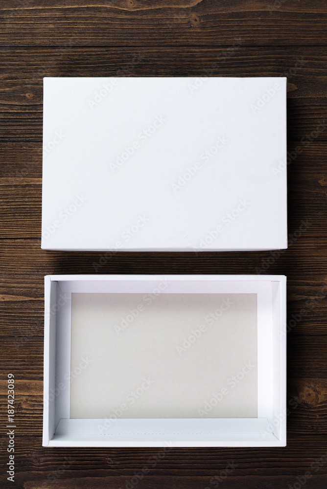 Fototapeta premium Empty white gift box or tray for mock up on dark wooden table with copy space.