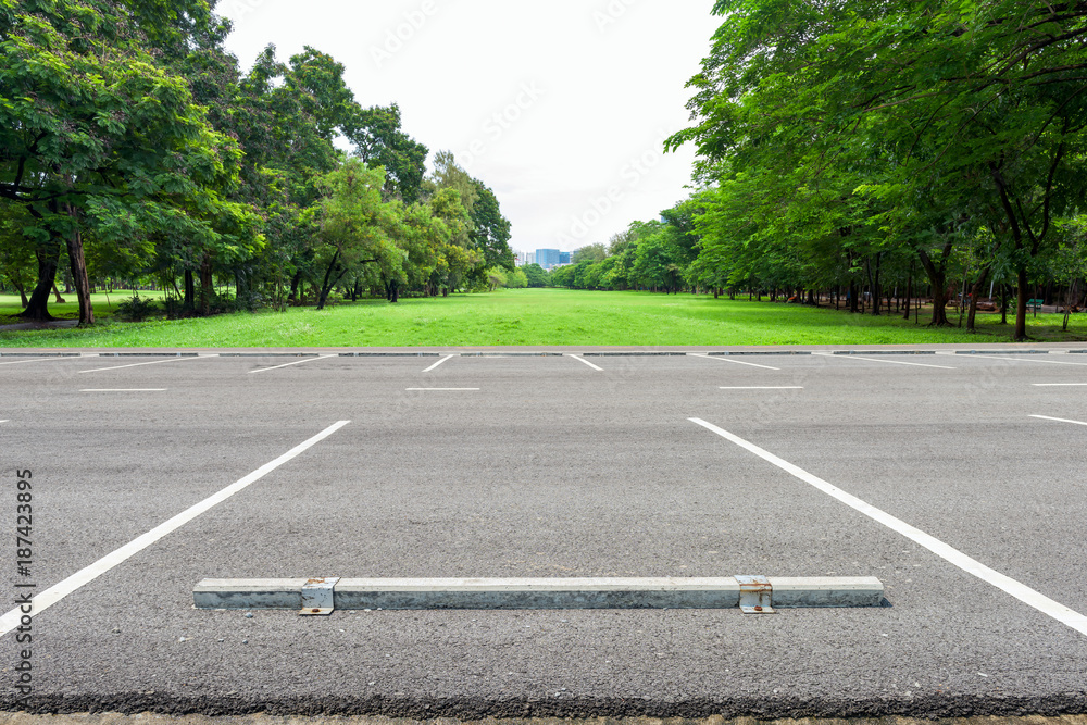 Obraz premium Empty parking lot against green lawn in city park